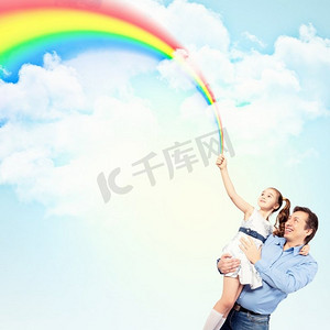 父亲抱着女儿和彩虹。幸福的父亲牵着女儿的手形象和彩虹