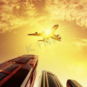 飞机飞在空中摄影照片_飞机在空中。在摩天大楼上空飞行的飞机。商务旅行概念