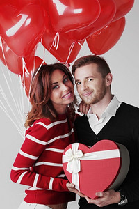 相爱的情侣。幸福地拥抱相爱的情侣，手持情人节礼物和一堆心形气球