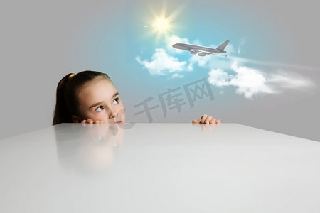 女孩和飞机在天空中。小可爱的女孩看飞行飞机