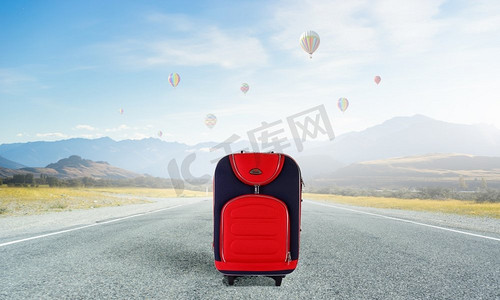 假期旅行行李箱摄影照片_红色行李箱在路上。红色行李箱上路的旅行理念