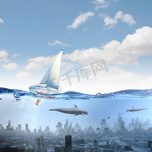 沉没的城市。漂浮的游艇和海豚在沉没的城市上空的水中游泳