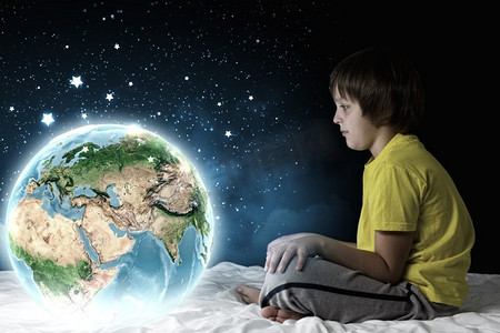 夜里做梦。可爱的男孩坐在床上做梦。这张图片的要素由美国宇航局提供