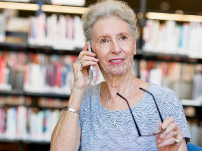 图书馆里拿着手机的老太太。给我的朋友打电话