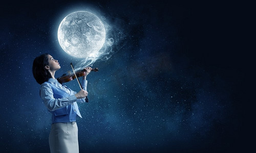 漂亮的小提琴手年轻女子演奏小提琴和满月在天空