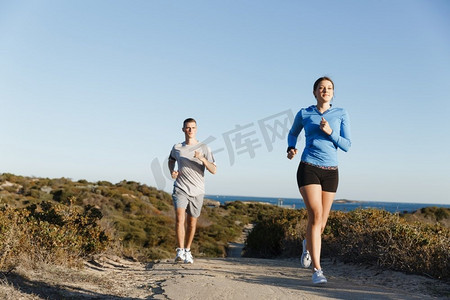 体育跑步者在海滩慢跑锻炼出与她的伙伴.适合女性健身模型慢跑沿着海洋与她的伙伴