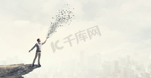 书摄影照片_手里拿着书的男人。年轻帅哥牵着书和人物飞了出去