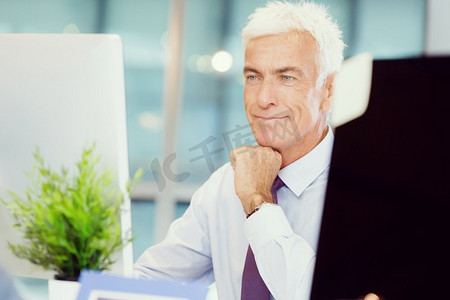 坐在电脑前办公摄影照片_坐在办公室里用电脑工作的商人。又一个在电脑前办公的日子