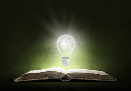 明亮的教育之光。打开的书和上方发光的灯泡