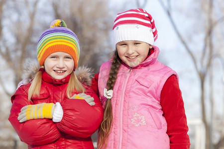 赛季摄影照片_两个可爱的女孩在冬季公园玩得开心。冬季活动