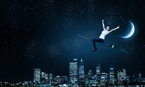 穿着休闲的少女骑着扫帚在高空飞翔。扫帚上的女孩