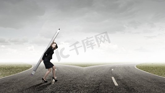 企业负担摄影照片_女人用巨大的铅笔。年轻的女商人携带大铅笔上回