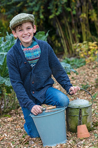 快乐的男孩儿，戴着帽子或平顶帽子，在菜地里用水桶、花园叉子和水壶园艺