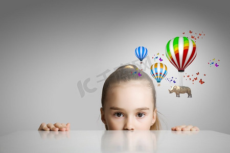 犀牛飞在气球上。小可爱的女孩看从桌子下面