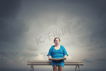 胖胖的女人。加码女人，手里拿着书，坐在板凳上