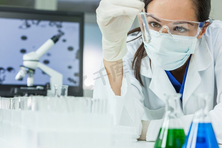 女医学或研究科学家或医生，在实验室或实验室中观察透明溶液的试管