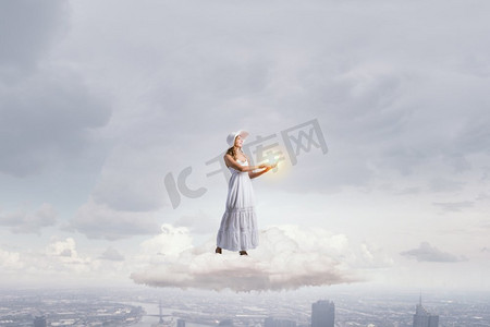 云层上摄影照片_使用笔记本电脑的女士。站在云端使用笔记本电脑的年轻女士