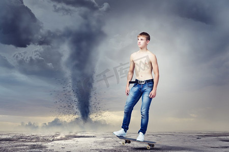 滑板上的少年。穿着牛仔裤的滑冰者在路上，背景是龙卷风