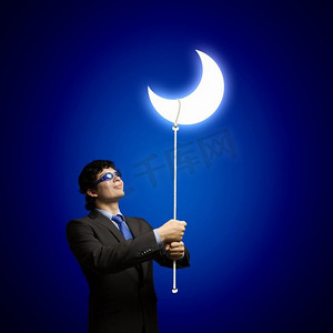 梦的概念。戴着护目镜看月亮的年轻商人形象