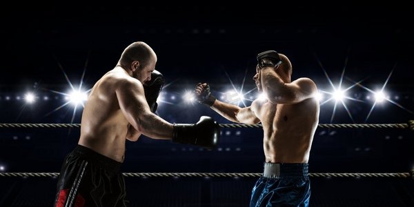 专业拳击比赛。在聚光灯混合媒体的竞技场上战斗的两个职业拳击手