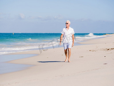 水里的衣服摄影照片_在阳光明媚的日子里，一个穿着白色衣服的男人在海滩上。海滩上美丽的一天