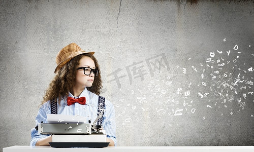 女作家。戴着眼镜的年轻滑稽女子在使用打字机