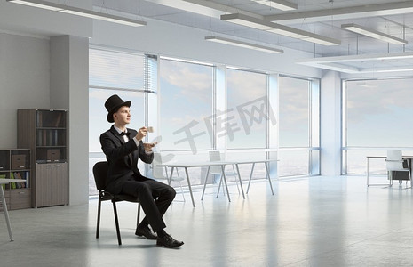 热腾腾摄影照片_气瓶里的商人喝着咖啡。一位商人在办公室休息，喝着一杯热腾腾的芳香咖啡