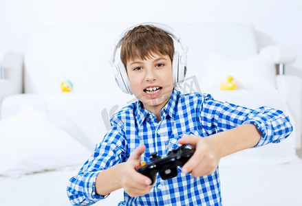 男孩玩游戏机。情绪孩子男孩坐在地板上玩游戏在操纵杆