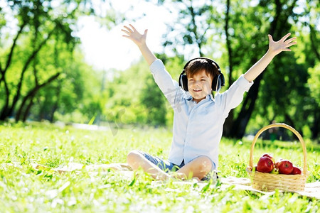 夏日公园里戴着耳机的快乐小男孩。天籁之声