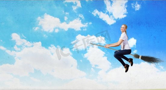 魔法扫把摄影照片_年轻又粗心。快乐的年轻女子飞行在天空的扫帚