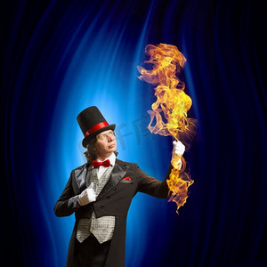 神奇的魔术师摄影照片_戴帽子的魔术师人魔术师的图像显示诡计反对颜色背景