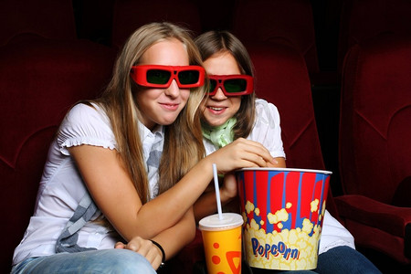 两个年轻女孩看电影在电影院