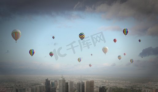 农药污染摄影照片_飞翔的气球。五颜六色的浮空器在现代城市上空的晴空中飞舞
