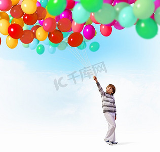 带着气球的可爱男孩。可爱的小男孩手持一串彩色气球的图片