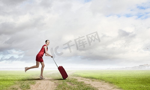 穿红衣服的女人。年轻女子穿着红色连衣裙，背着红色行李箱
