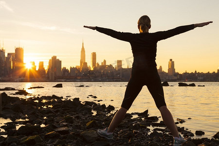 日出时分在纽约市天际线前锻炼的年轻女子或女孩的剪影
