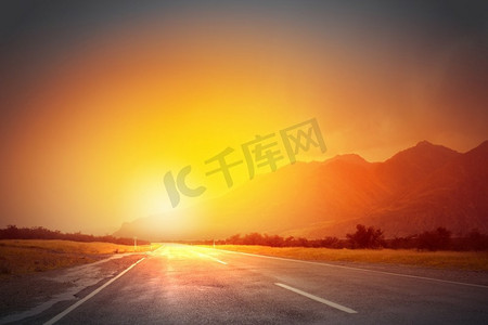 太陽升起摄影照片_日出在路上。空荡荡的柏油路和太阳从天际线升起