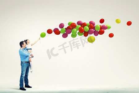 牵着气球摄影照片_父亲牵着女儿的手。幸福的父亲牵着女儿和气球的形象
