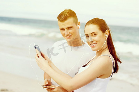 智能电话摄影照片_户外有移动智能手机的跑步者夫妇。有移动智能电话的赛跑者的年轻夫妇户外在海滩