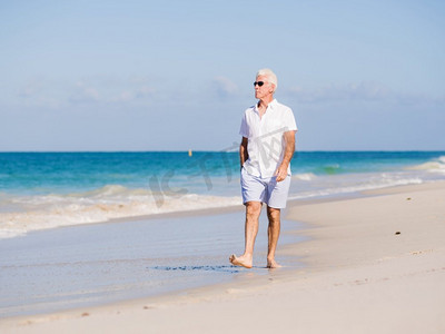 在阳光明媚的日子里，一个穿着白色衣服的男人在海滩上。海滩上美丽的一天