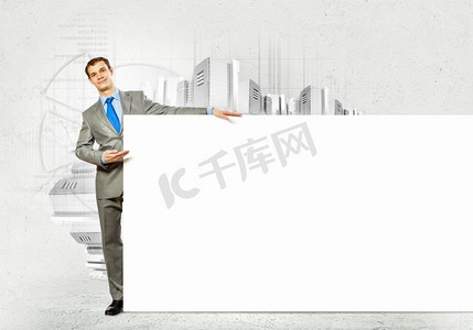 打着空白横幅的商人。拿着空白横幅的商人站在城市风景的对立面。文本的位置