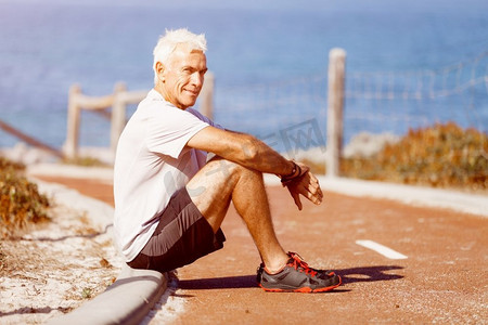 穿着运动服的男人坐在海滩上。穿着运动服的男人独自坐在海滩上休息一分钟