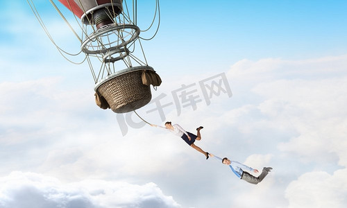 女人和男人在浮空器上飞行。年轻的女商人和男人骑着五颜六色的浮空器在天空中高高飞行