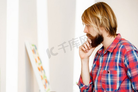 一名男子站在画廊里凝视着艺术品。站在画廊里凝视抽象艺术品的人