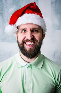 十大展架摄影照片_快乐的大胡子男人。圣诞节庆祝肖像--戴着圣诞帽的留着胡须的年轻人