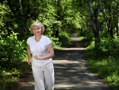 健身跑步老人摄影照片_老太太喜欢在公园里跑步。健康的生活方式
