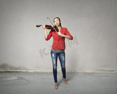 会红色摄影照片_漂亮女人会拉小提琴。穿着红色夹克的年轻漂亮女子在拉小提琴