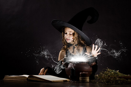 女巫动图摄影照片_万圣节女巫。小万圣节女巫在锅上读魔术