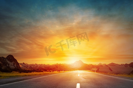 太陽升起摄影照片_日出在路上。空荡荡的柏油路和太阳从天际线升起