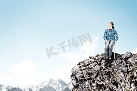 隔离的概念。一位穿着休闲服装的年轻女子坐在岩石上